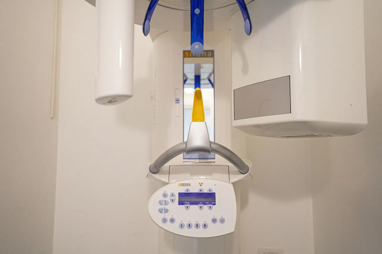 Ortopantomografo Sirona bianco con supporti blu, mordente giallo e pannello di controllo nello Studio Dentistico Dott. Biagio Rapone